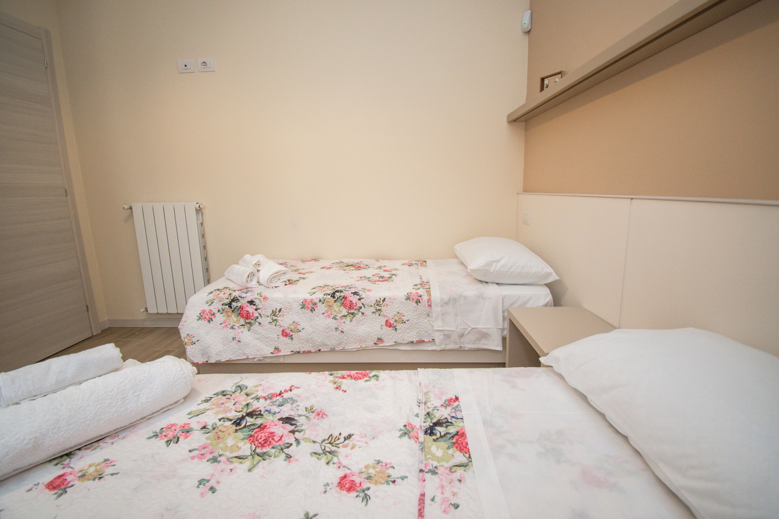 Un dormitorio con dos camas, un radiador y una puerta.