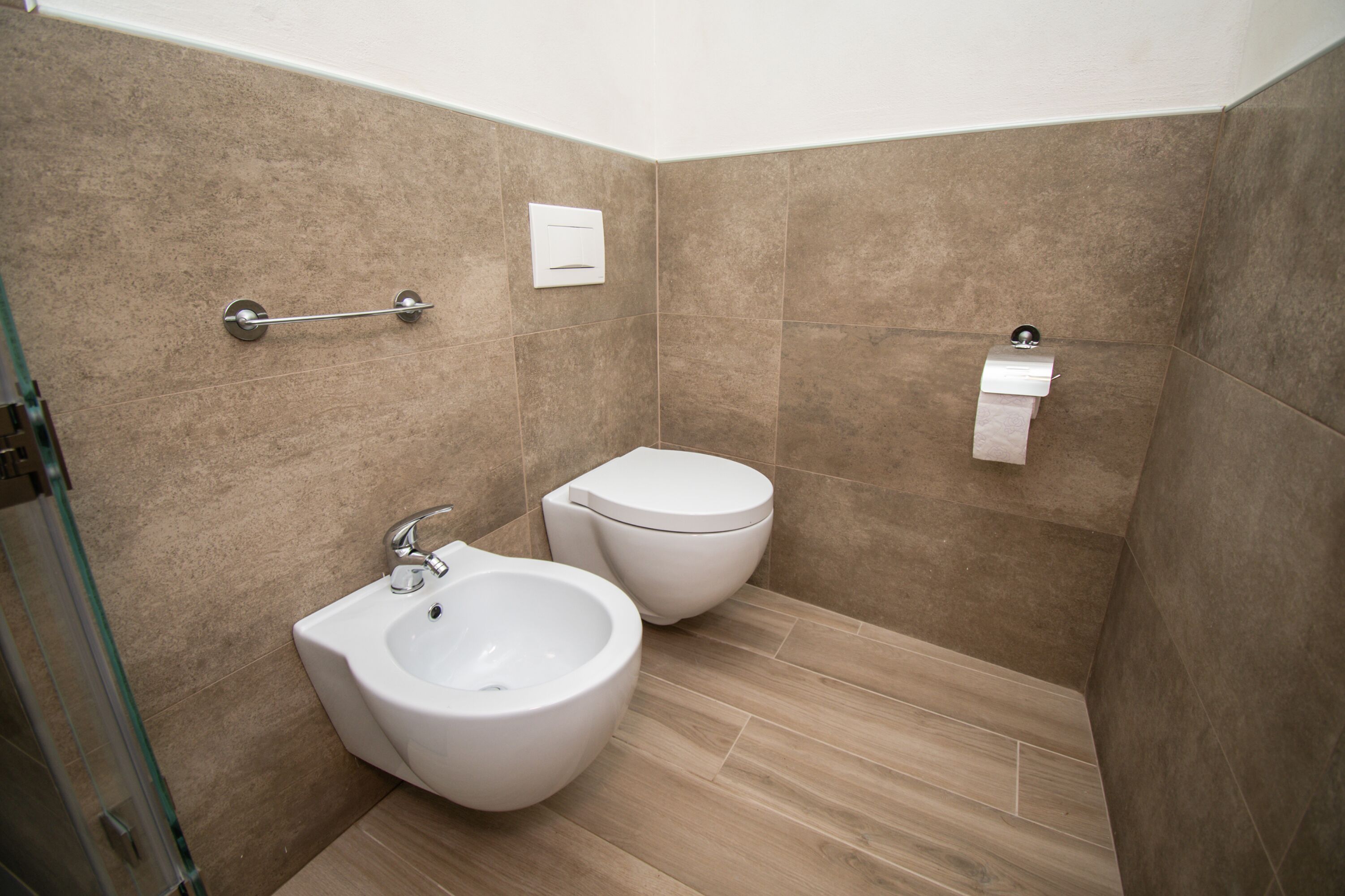 Une salle de bain moderne équipée d’un bidet, de toilettes et d’une douche à parois en verre.