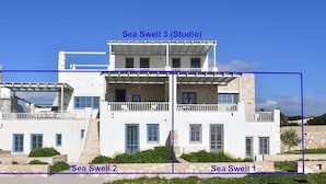 Un edificio de tres pisos con balcones y fachada de piedra, identificado como Sea Swell 3 (Estudio).