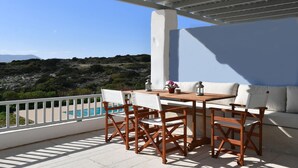 Una terraza con piscina, muebles de madera y un sofá blanco.