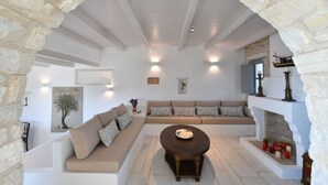 Una sala de estar acogedora con un arco de piedra, un sofá beige, una mesa de centro de madera y una chimenea con adornos.