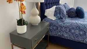 Ein Schlafzimmer mit einem Bett, einem Nachttisch mit einer Lampe und einer Zimmerpflanze.