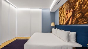A hotel room with a large bed, a wall-mounted lamp, and a decorative wall piece.