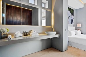 A modern bathroom with a large mirror, a vessel sink, and a white vanity.