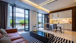 A modern living room with a sofa, a coffee table, and a view of the outdoors through large windows.