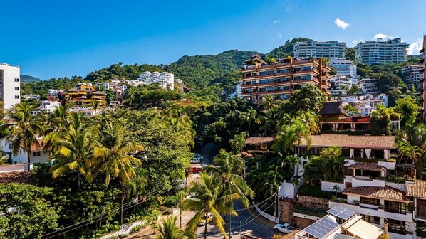 A residential area with multi-story buildings, palm trees, and a clear sky.