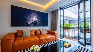 A modern living room with a leather sofa, a glass coffee table, and a large window with a view of a balcony.