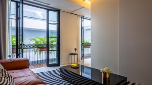 A modern living room with a sofa, a coffee table, and a view of a balcony with plants.