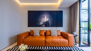 Una sala moderna con un sofá de cuero, un cuadro abstracto grande y un ventanal que da a un balcón.