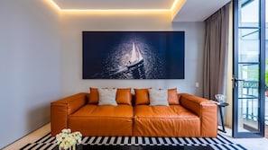 Una sala moderna con un sofá de cuero, un cuadro abstracto grande y un ventanal que da a un balcón.