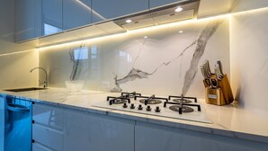 Una cocina moderna con salpicadero de mármol, electrodomésticos de acero inoxidable y un juego de cuchillos.
