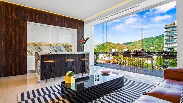 Una sala de estar moderna con un ventanal grande, una mesa de centro de vidrio y un sofá.