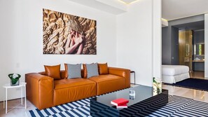 Una sala de estar moderna con un sofá de cuero, una mesa de centro de vidrio y un cuadro abstracto grande en la pared.