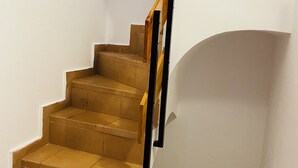 A staircase with wooden steps and a black handrail, leading to a landing with a white wall and a small wooden shelf. - QUIET APARTMENT  (Canet de Mar)