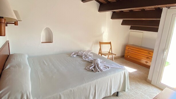 A bedroom with a bed, a wooden chair, a nightstand, and a window. - QUIET APARTMENT  (Canet de Mar)