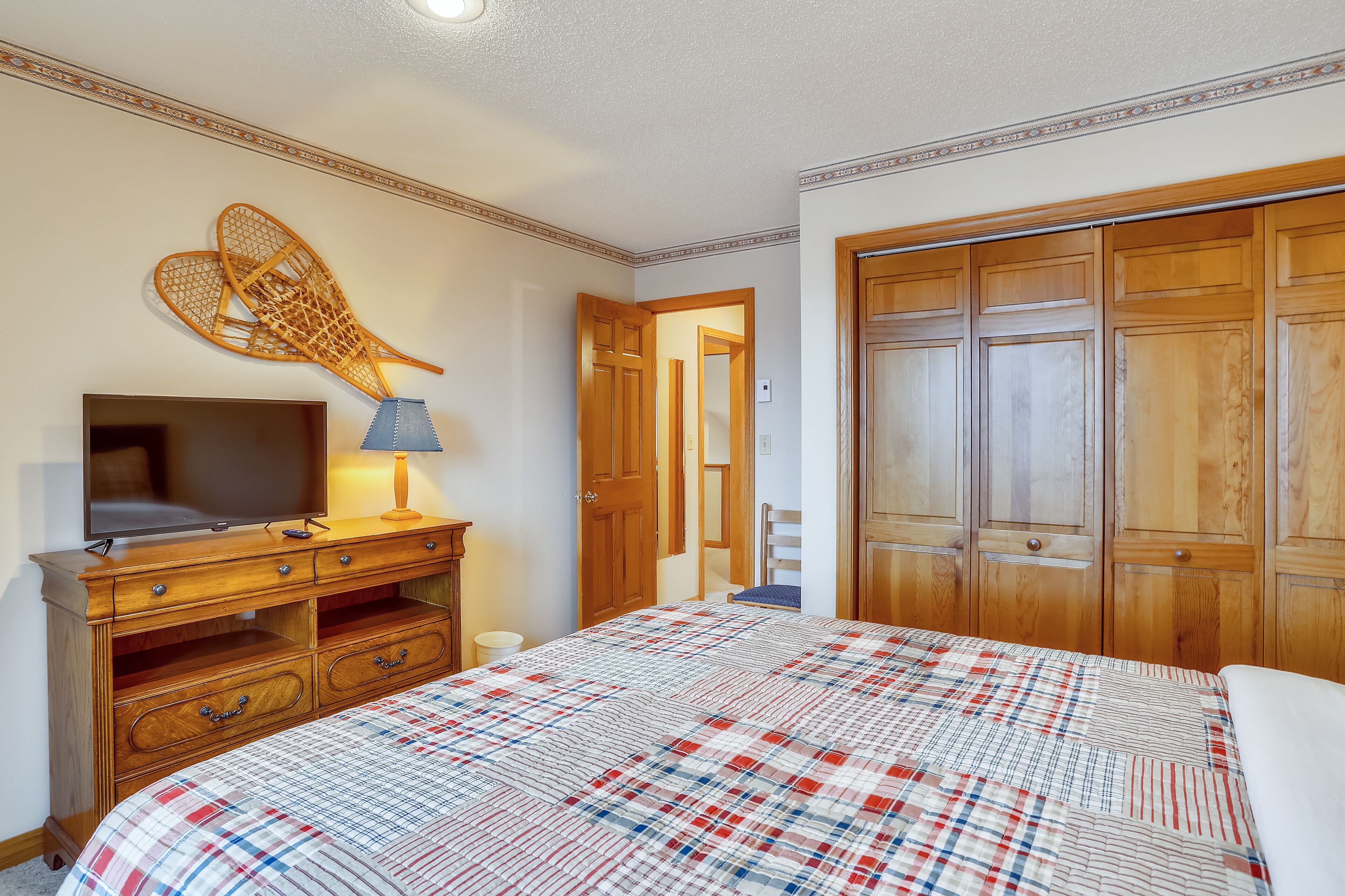 Een slaapkamer met een bed, een televisie, een dressoir en een kledingkast.