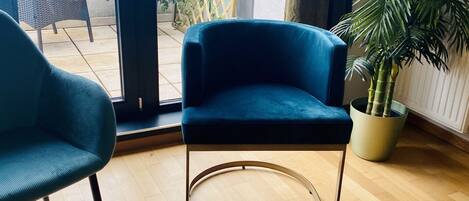 A modern room with a blue chair, a glass table, and a potted plant.