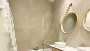 A modern bathroom with a bathtub, two sinks, and a large mirror. - Luxury Green Penthouse Center - Parking (Luxembourg City)