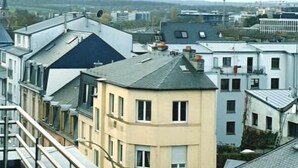 A view of a residential area with multi-story buildings, a visible staircase, and a distant church spire. - Luxury Green Penthouse Center - Parking (Luxembourg City)