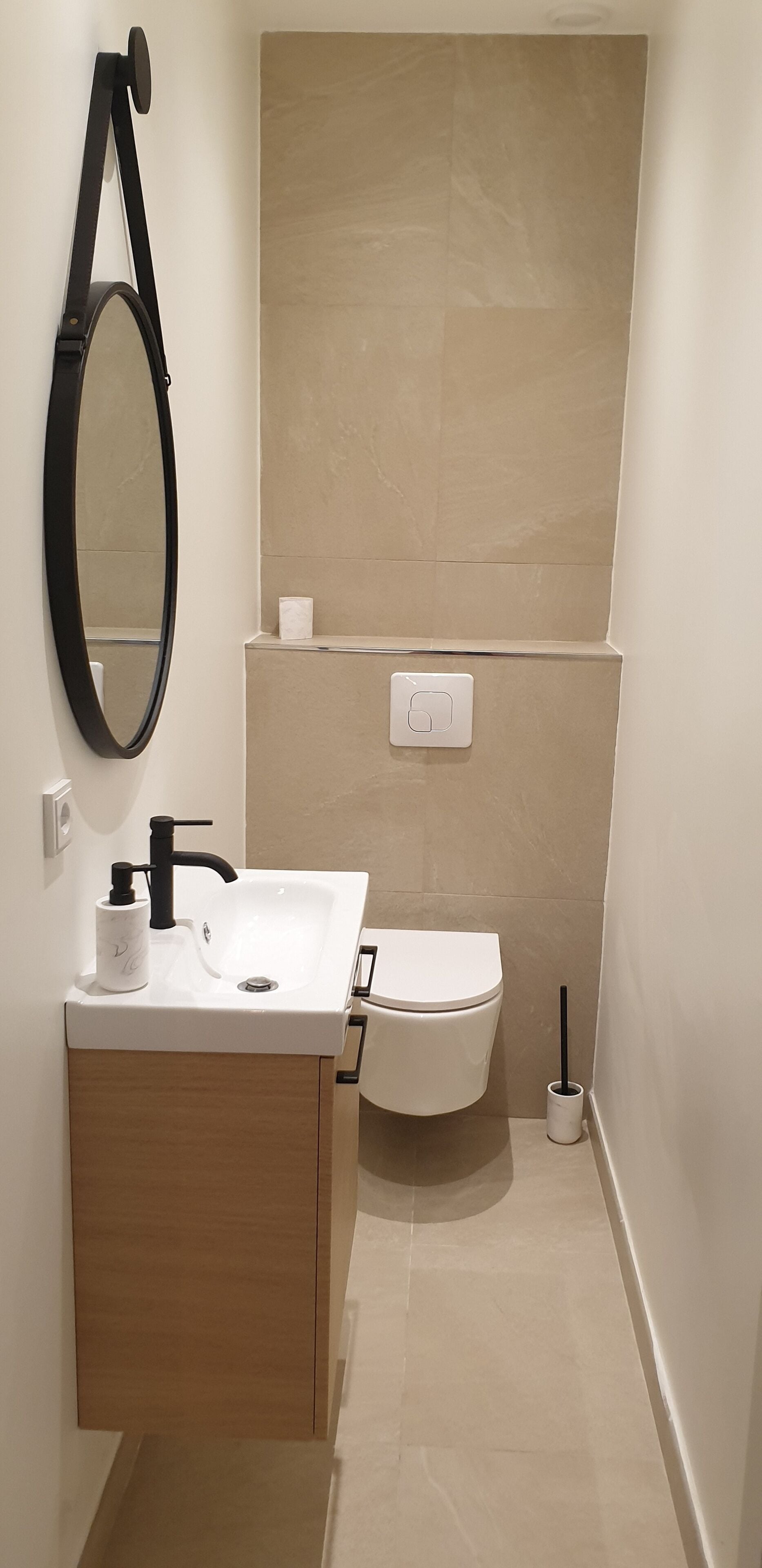 Un baño moderno con lavamanos blanco, grifo negro y espejo.
