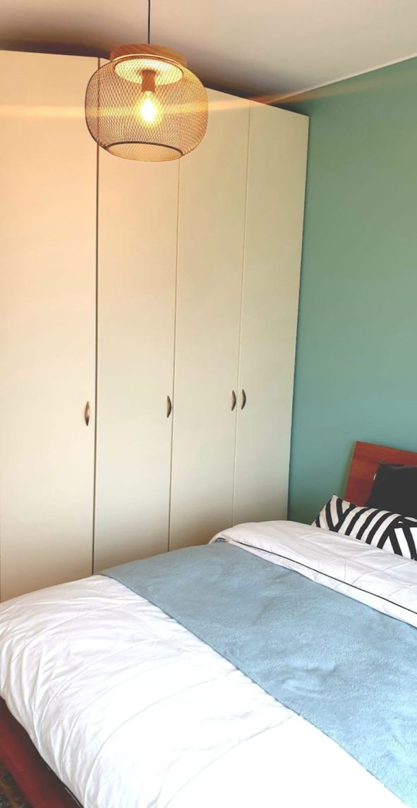 Un dormitorio con cama, armario e iluminación colgante.