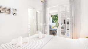 Un dormitorio moderno con una cama grande, una mesita de noche y vistas al exterior a través de un ventanal.