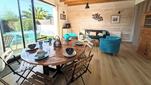 A spacious living area with a wooden ceiling, a dining table set with bowls and cups, a blue sofa, and a television on a cabinet. - House 100m from the beach and 500m from the port of St Jacques, les gîtes de Rhuys  (Sarzeau)