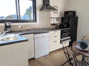 Une cuisine moderne équipée d’un lave-vaisselle, d’un four, d’un four à micro-ondes et d’un coin repas avec une table et des chaises en bois.