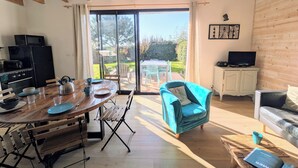 A modern kitchen with a dining area, a blue chair, and a TV. - House 100m from the beach and 500m from the port of St Jacques, les gîtes de Rhuys  (Sarzeau)