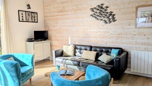 A living room with a wooden wall, a black leather sofa, and two blue armchairs. - House 100m from the beach and 500m from the port of St Jacques, les gîtes de Rhuys  (Sarzeau)