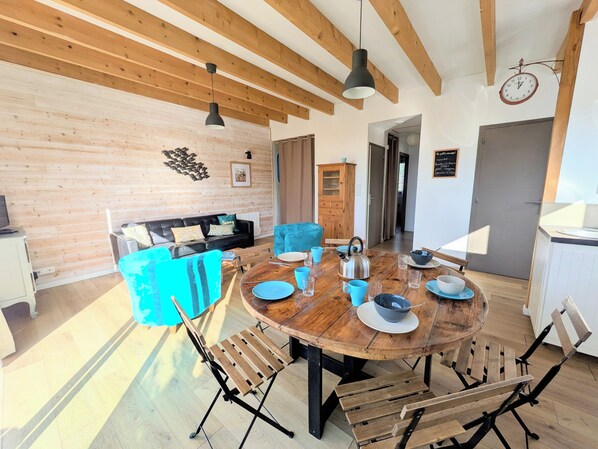 Un salon moderne avec un plafond en bois, une table de salle à manger ronde en bois et un canapé bleu.