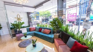 A modern lobby with a blue sectional sofa, a glass coffee table, and potted plants. - Big Home Hotel (Da Nang Municipality)