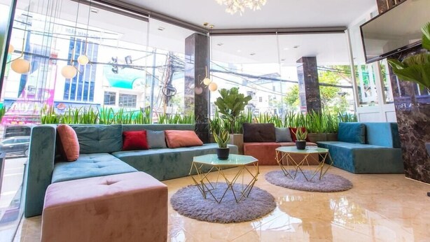 A modern lobby with a sectional sofa, two round tables, and a chandelier. - Big Home Hotel (Da Nang Municipality)