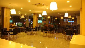 A spacious indoor area with multiple tables and chairs, ceiling lights, and a visible air conditioning unit. - Big Home Hotel (Da Nang Municipality)