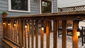 A wooden deck with a railing, string lights, and a potted plant. - Bright Bohemian Home w/ Parking + Deck Near Forsyth Park by Lucky Savannah (Savannah)