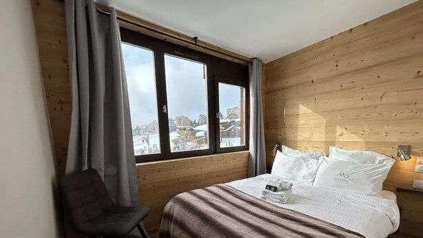 A bedroom with a bed, a chair, and a window with curtains. - Apt, 1206 _ Properties Mont Amour  (Morzine)