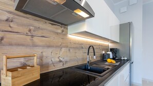 Een moderne keuken met een zwart aanrecht, een roestvrijstalen spoelbak en een houten spatwand.