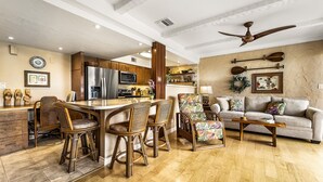Amplia sala de estar con un sofá grande, una mesa de comedor con sillas y una zona de cocina con refrigerador y microondas.