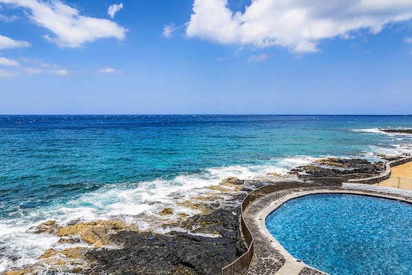 Relax by the infinity pool overlooking the ocean, surrounded by a scenic rocky shoreline.