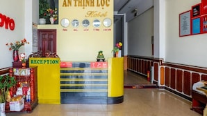 Ein Empfangsschalter mit einem Schild, das "AN THINH LOC Hotel" zeigt, und Uhren, die verschiedene Zeitzonen anzeigen.