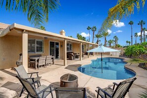A residential property with a swimming pool, outdoor furniture, and palm trees. - Minutes to Coachella · Pool & Spa · 5BR Sleeps 12 (Indio)