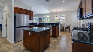 A modern kitchen with a central island, stainless steel appliances, and wooden cabinets.