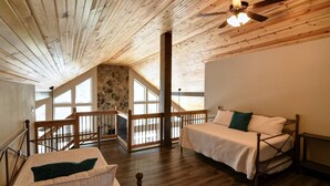Ein Schlafzimmer mit Holzboden, einem Bett, einem Fenster und einer Steinwand.