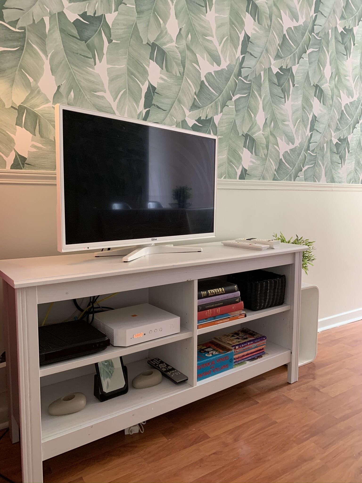 Een witte entertainmentkast met een flatscreentelevisie, een spelconsole en diverse videospelletjes.