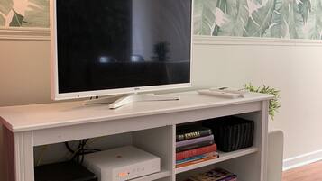 Een witte entertainmentkast met een flatscreentelevisie, een spelconsole en diverse videospelletjes.