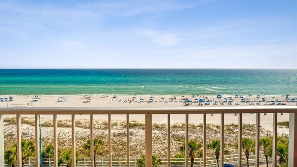 A beach view from a balcony with a railing, palm trees, and beach umbrellas. - The Summit 727 (Panama City Beach)
