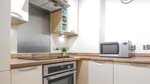 Eine kleine Küche mit eingebautem Backofen, Mikrowelle und einer Holzauskładung.