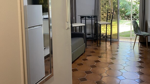 Un espacio habitable compacto con kitchenette, comedor y puerta corrediza de vidrio que da a un jardín.