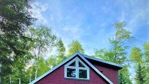 A red cabin with a gabled roof, a front porch, and a small window. - Rangeley Getaway (Dallas Plantation)