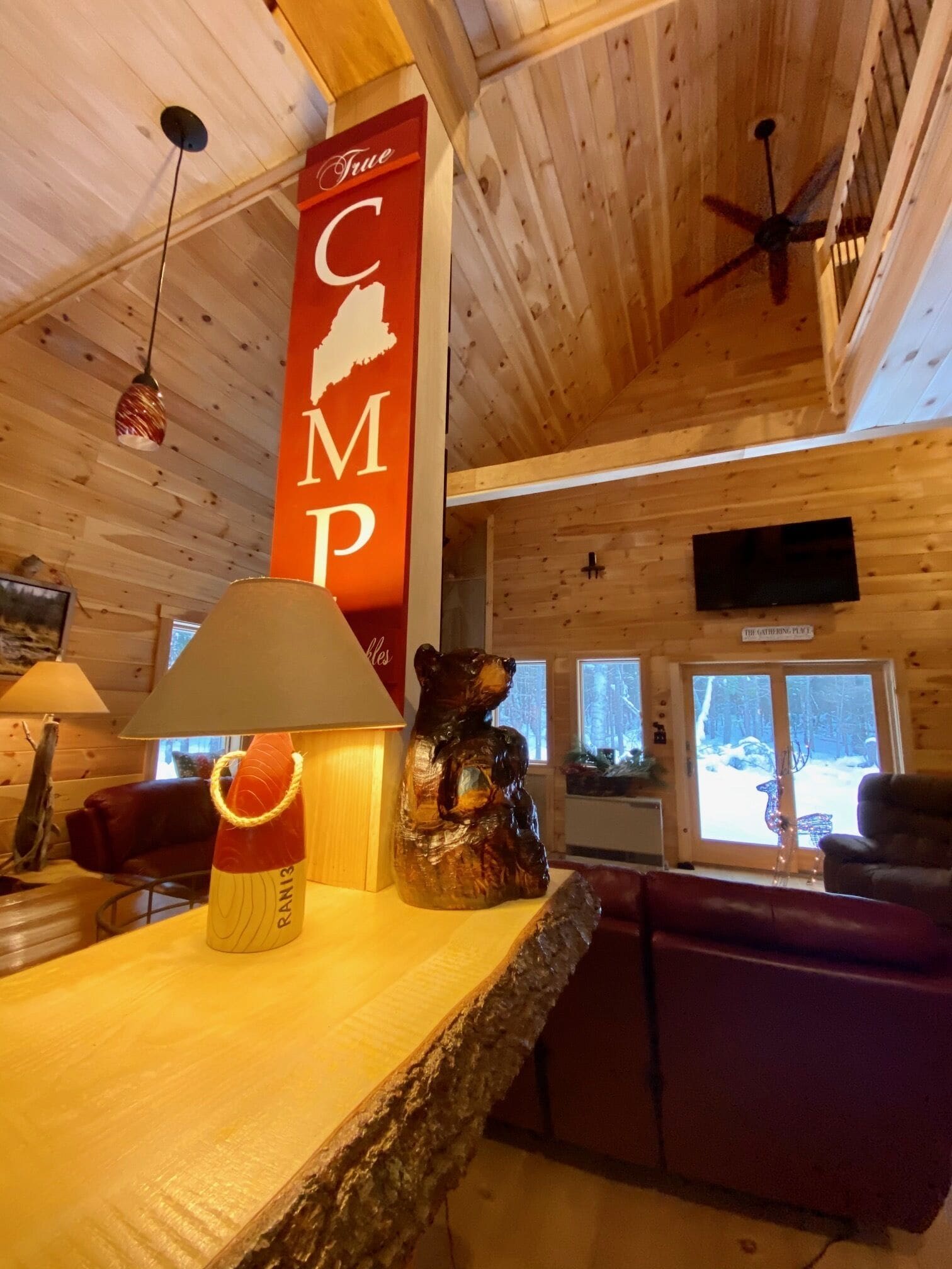 L’intérieur d’un chalet en bois, avec une sculpture d’ours, une lampe, une enseigne sur laquelle on peut lire « True CMP » et un téléviseur.